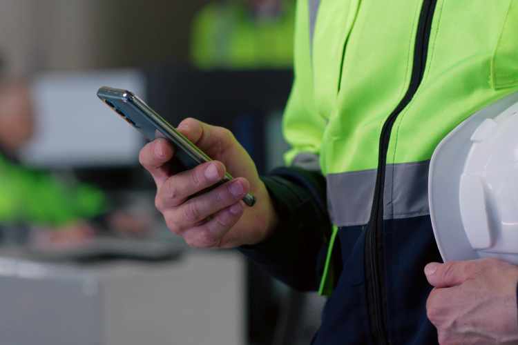 Byggare står med en mobiltelefon i handen