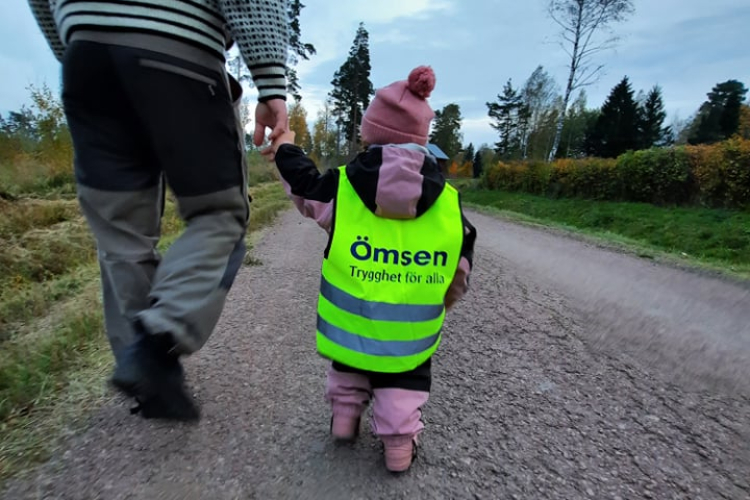 En man går med ett litet barn som har en reflexväst