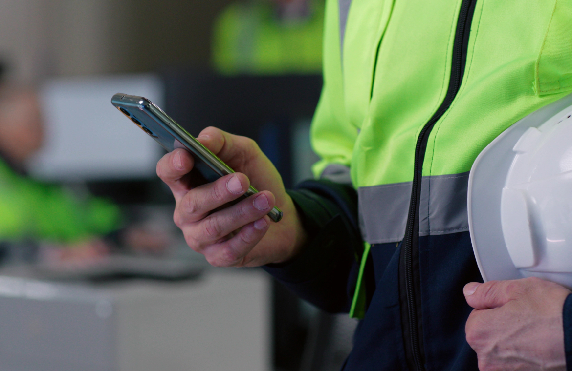 Byggare står med en mobiltelefon i handen